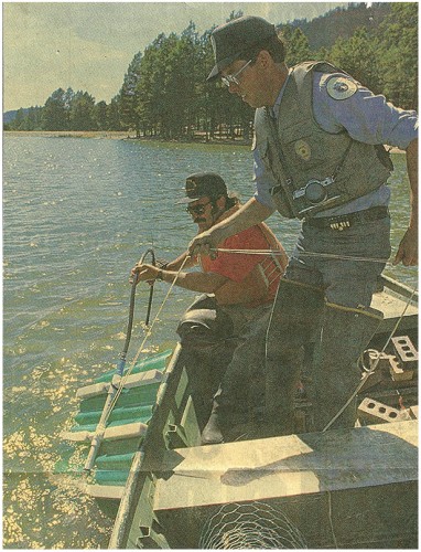 Game and Fish officer Jack Kelly and T.J. Jimerson lower a diffuser into the depths of Fenton Lake in the Jemez Mountains. Photo by Bill Dyroff/Journal