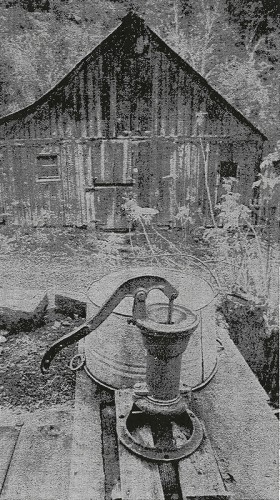 Barn with Dutch doors stands behind pump which still supplies water
